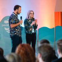Man and women with floral shirt presenting in from of audience