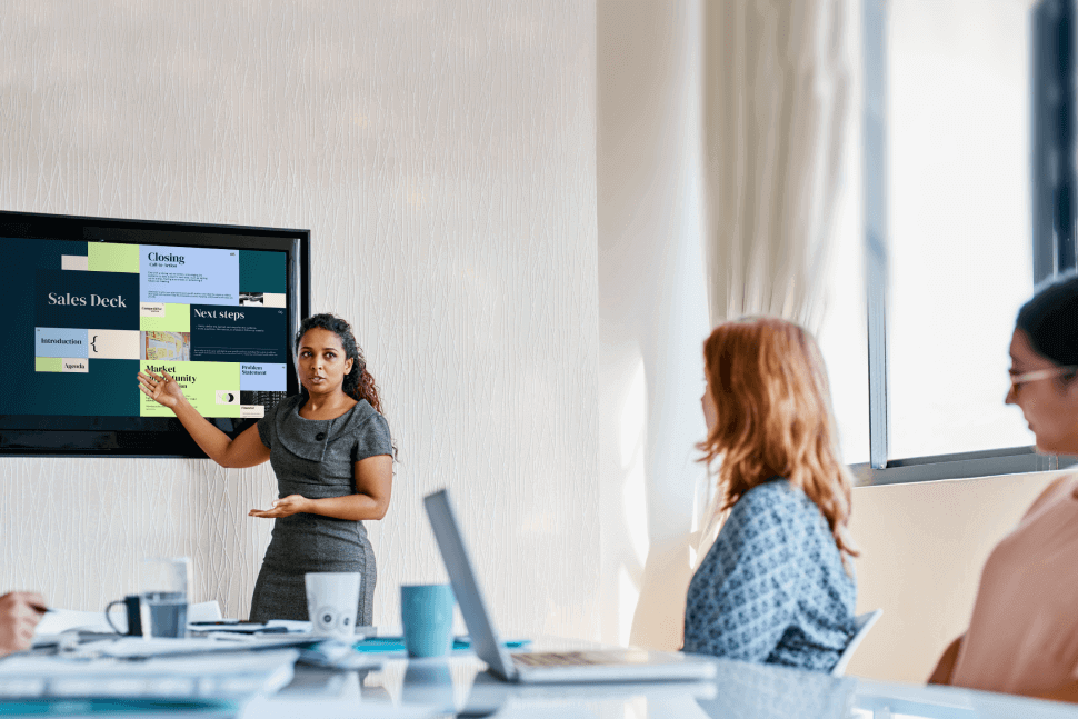 Woman in a meeting presenting in a monitor a Sales deck presentation