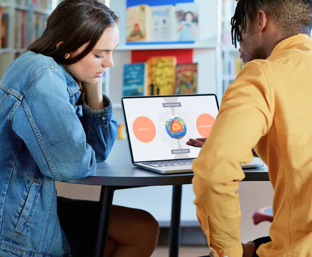 two students discussing a Prezi presentation on a laptop
